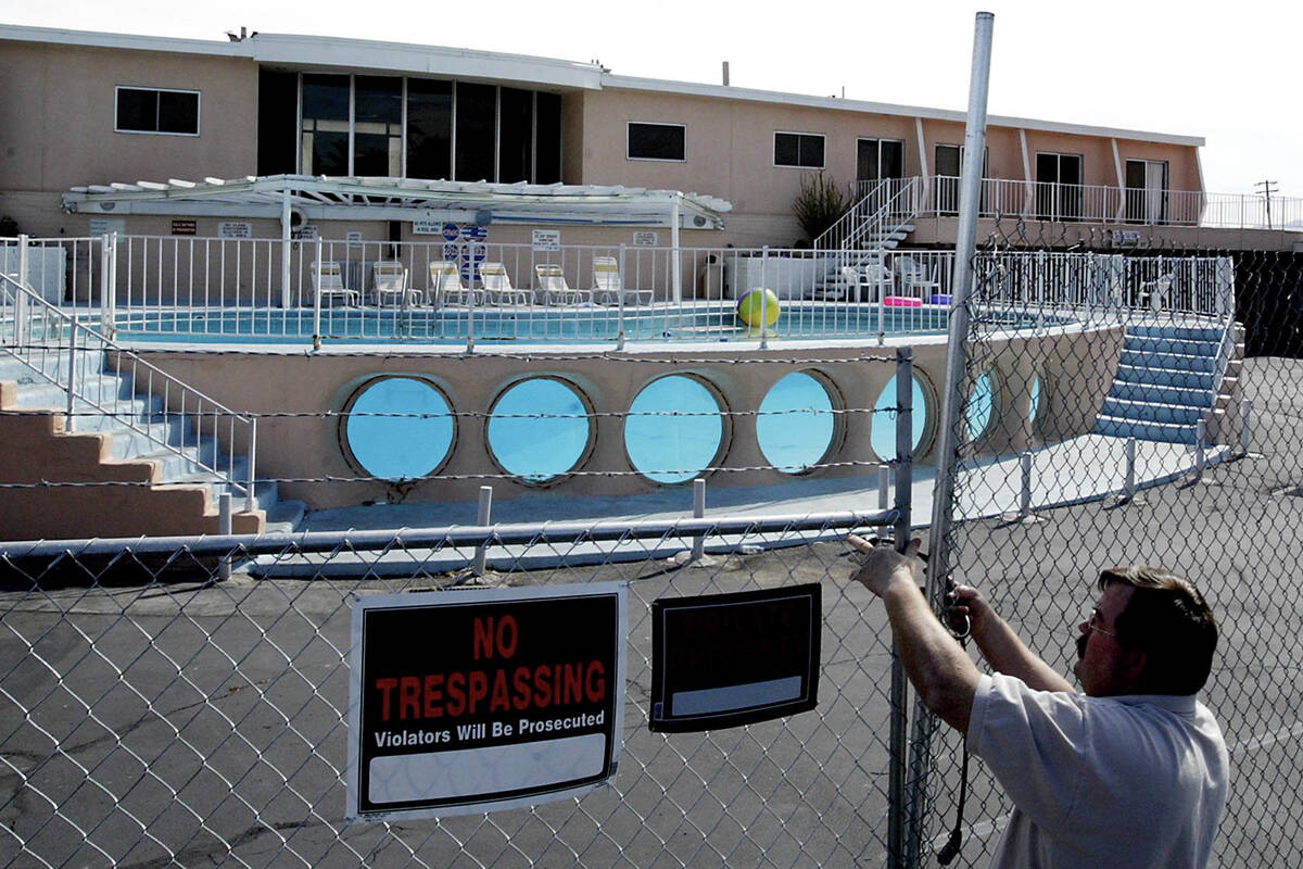 A worker locks the entrance to the Glass Pool Inn after making repairs to the gate of the close ...