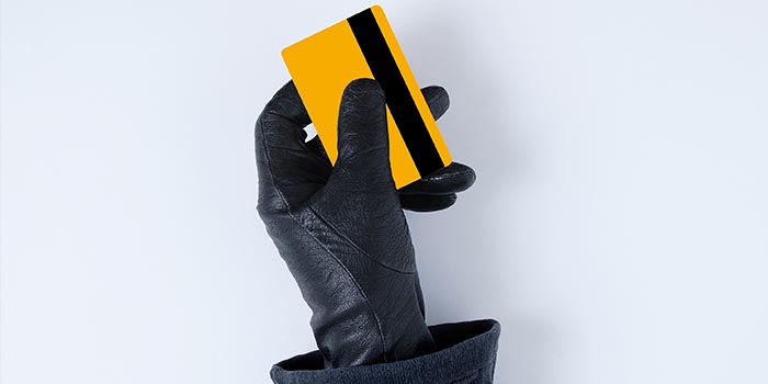 A person with glove holds a credit card